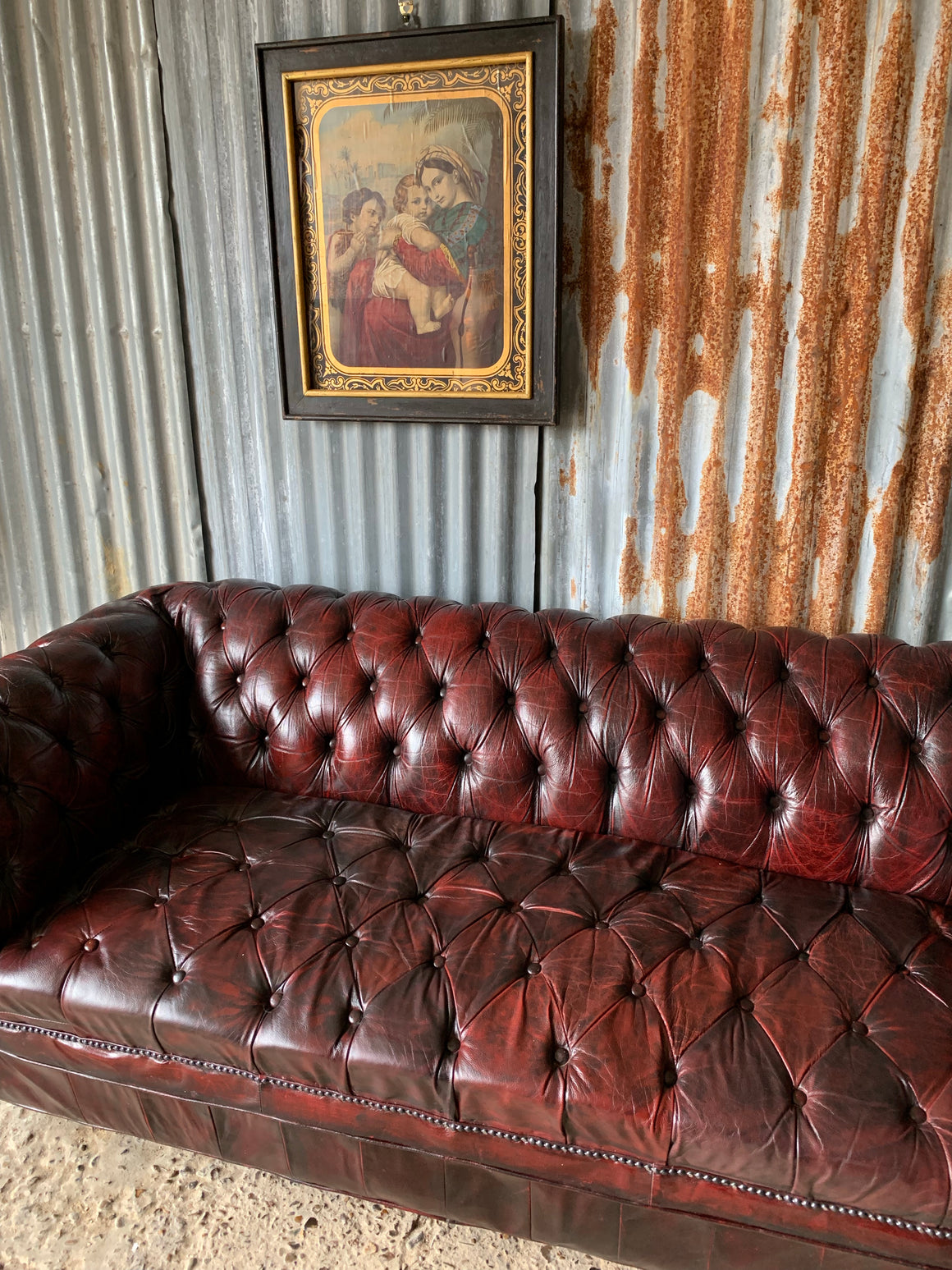 An oxblood three seater Chesterfield sofa with button back and seat