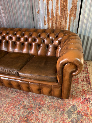 A brown three seater Chesterfield sofa with button back