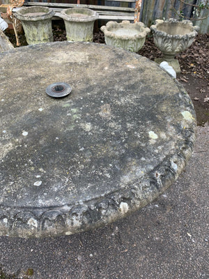 A cast stone round top pedestal garden table