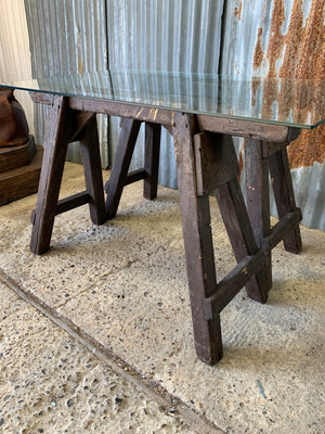 A wooden trestle base table with glass top