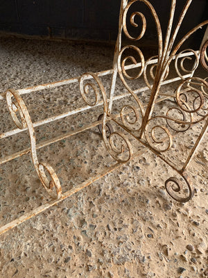 A weathered white wrought iron console table with glass top