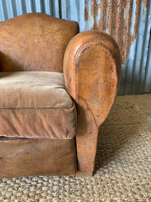 A tan leather club chair with moustache back