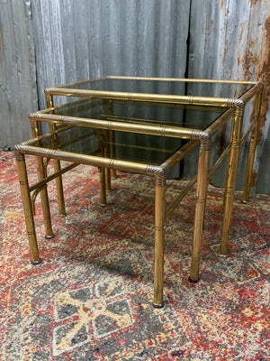 A brass and glass Hollywood Regency nest of faux bamboo tables