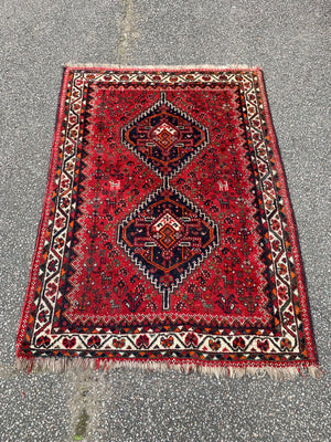 A red ground Persian rectangular rug with double diamond design- 158cm x 111cm