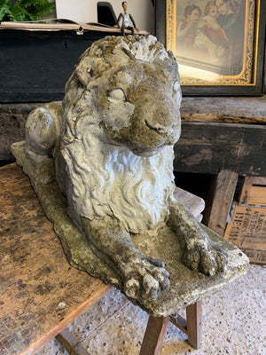 A pair of weathered cast stone recumbent lion statues
