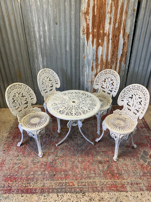 A white cast metal garden table and four chairs