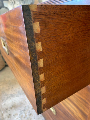 A campaign style chest of drawers with leather top