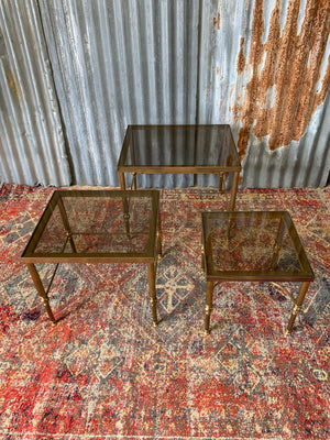 A brass and smoked glass Hollywood Regency nest of tables