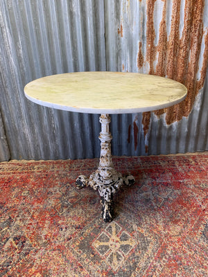 A dolphin base cast iron garden table with marble top