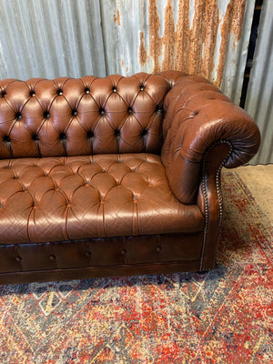 A brown two seater Chesterfield sofa with button back and seat