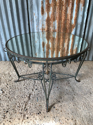 A circular wrought iron table with mirrored top