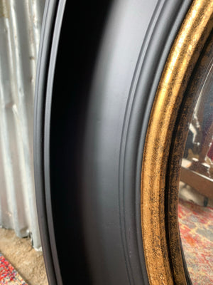 A large black and gold convex mirror