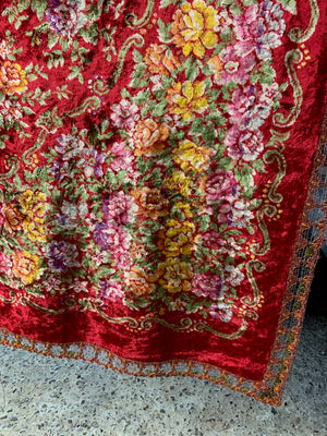 A large red velvet throw with floral decoration