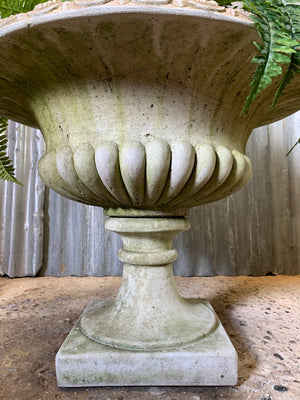 A pair of large gadrooned egg and dart cast stone urns