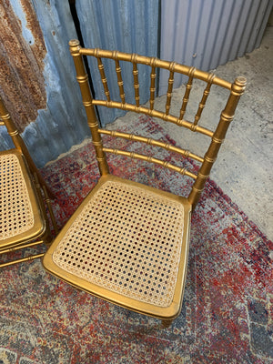 A set of four faux bamboo chairs with cane seats