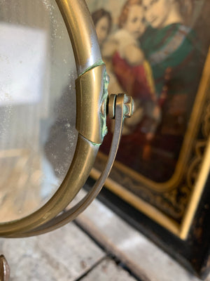 An adjustable brass grooming mirror