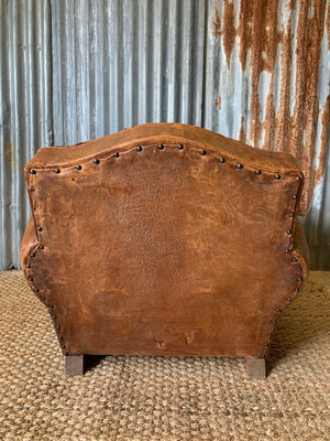 A tan leather club chair with moustache back