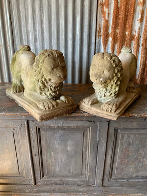 A pair of weathered cast stone lion statues