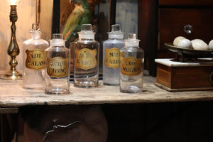 A collection of five hand painted glass apothecary bottles
