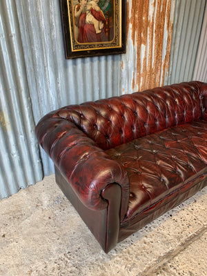 An oxblood three seater Chesterfield sofa with button back and seat