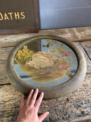 A large hand-painted circular mirror with swans and swallows