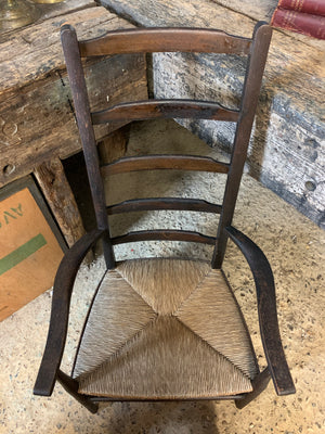 A low ladder back armchair with rush seat and footstool