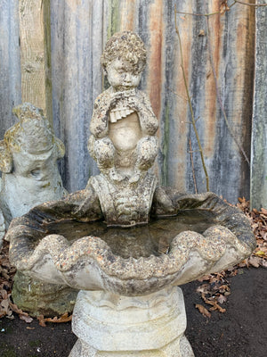 A cast stone bird bath with the figure of a fawn