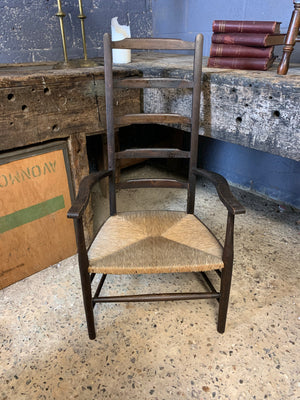A low ladder back armchair with rush seat and footstool