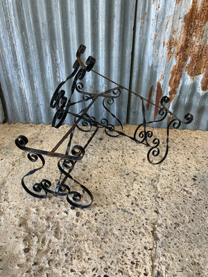A weathered black wrought iron plant stand