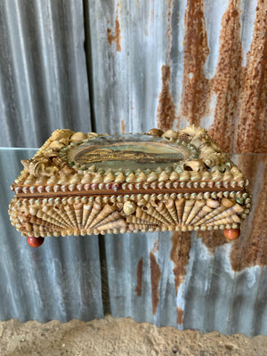 A large seashell encrusted trinket box with domed harbour scene