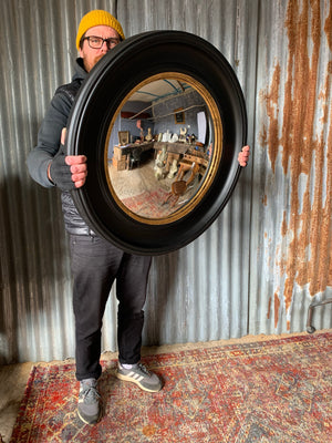 A large black and gold convex mirror