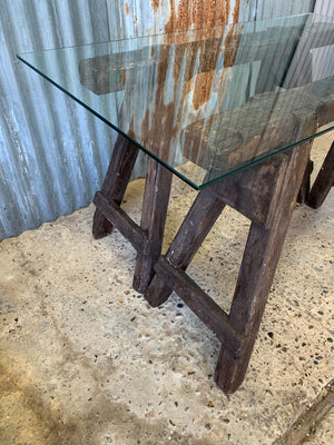 A wooden trestle base table with glass top