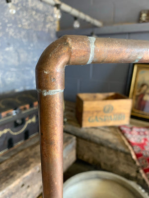 A vintage industrial copper pipe clothing rack