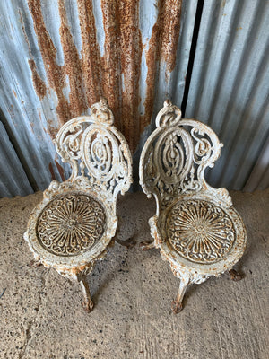 A pair of white cast iron Coalbrookdale chairs and complimentary bistro table