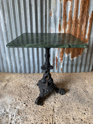 A cast iron dolphin bistro table with Verde Indio green marble top