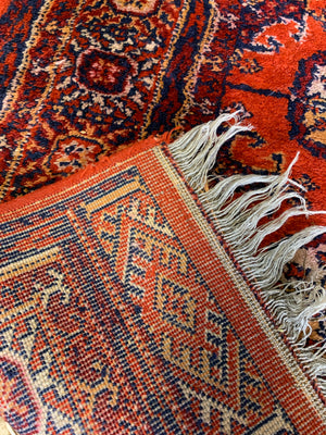 A Persian orange-red ground rectangular rug with multiple lozenge