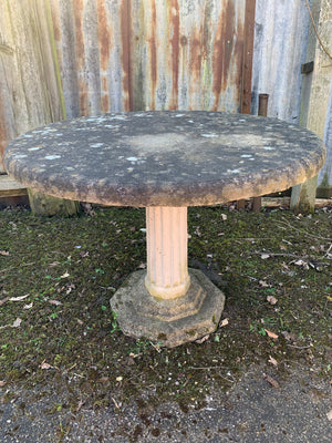 A large round weathered circular stone pedestal table