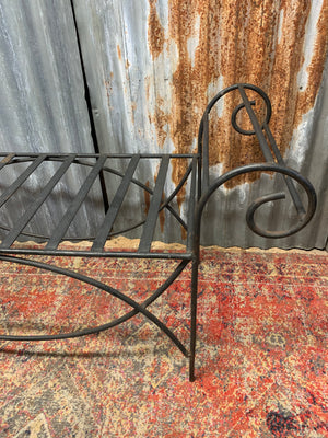 A wrought iron strapwork bench with scrolled arms
