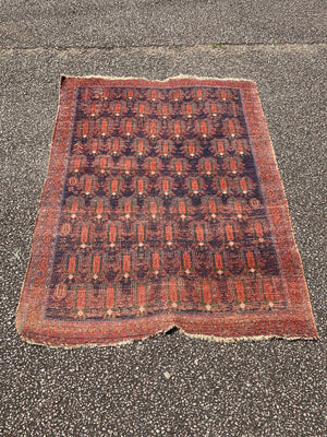 A hand woven Persian red ground small rectangular rug