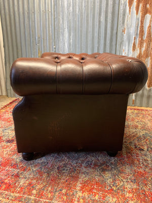 A brown Chesterfield armchair with button back and seat