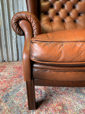 A brown wingback Chesterfield armchair with button back