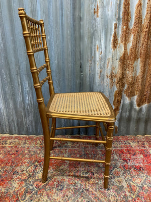 A set of four faux bamboo chairs with cane seats