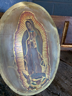 An oval painting on metal of The Madonna of Guadalupe