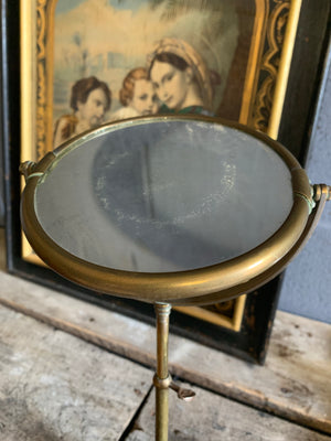 An adjustable brass grooming mirror