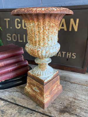 A white cast iron pedestal urn