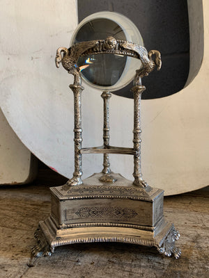 A large fortune teller's crystal ball on a silver plate swan stand