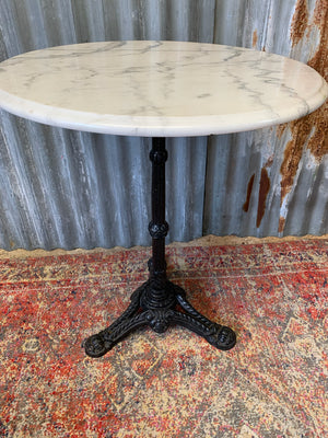 A black cast iron bistro table with marble top