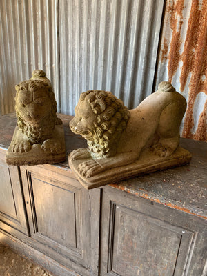 A pair of weathered cast stone lion statues