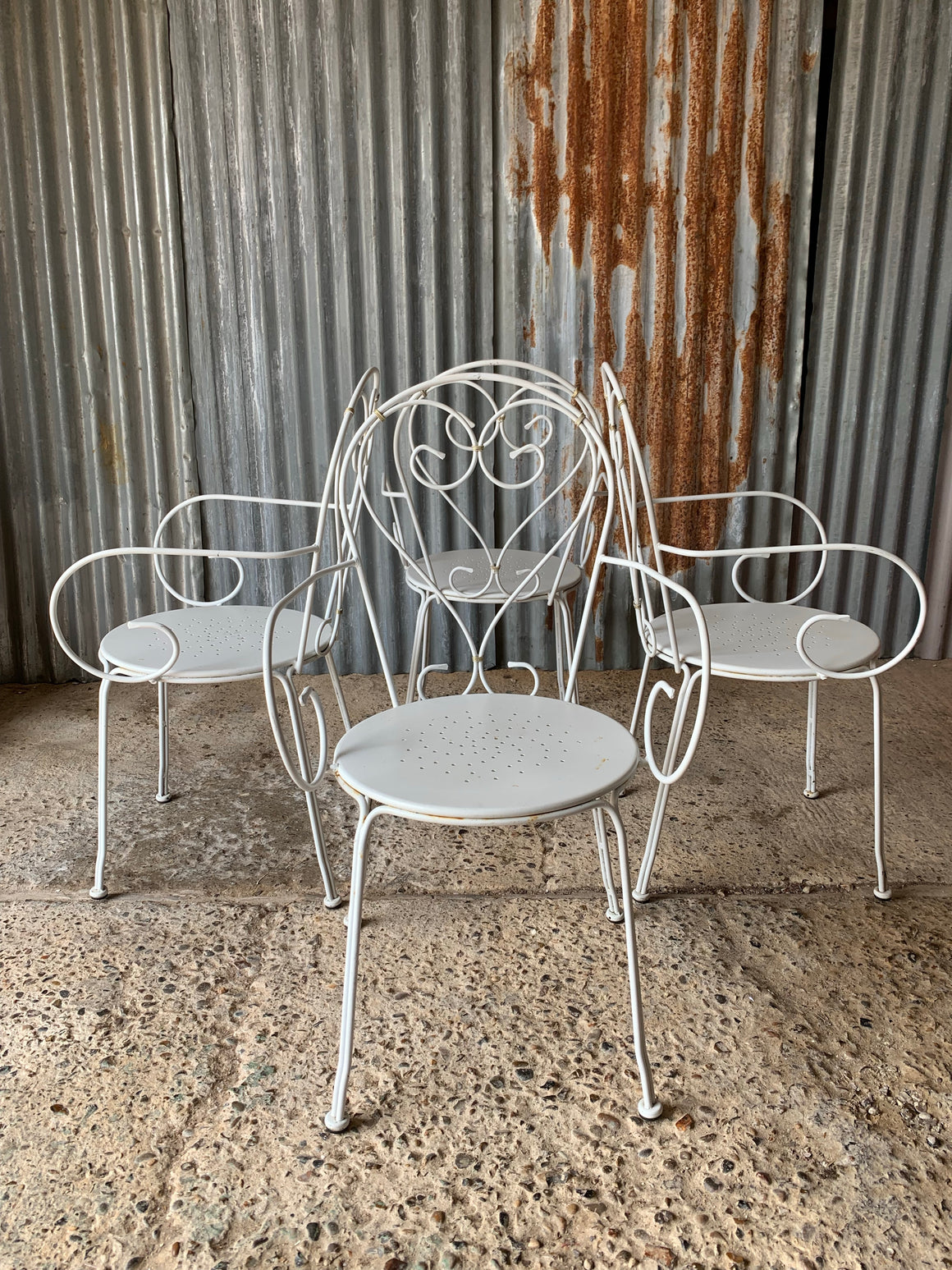 A set of four French white wire work garden chairs