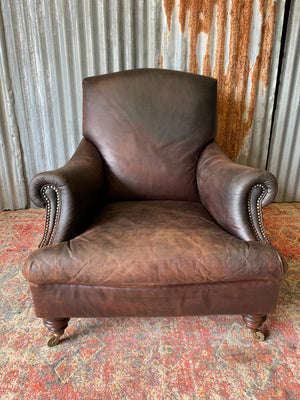 A deep leather armchair raised on castors